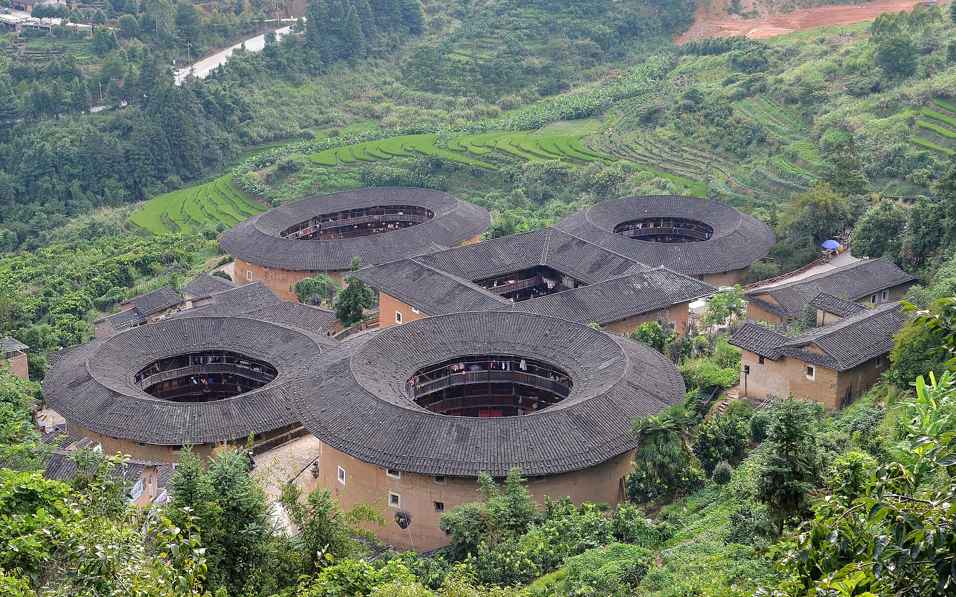 The five earth buildings of Tianluokeng Tulou cluster sit among terraced fields in Fujian.