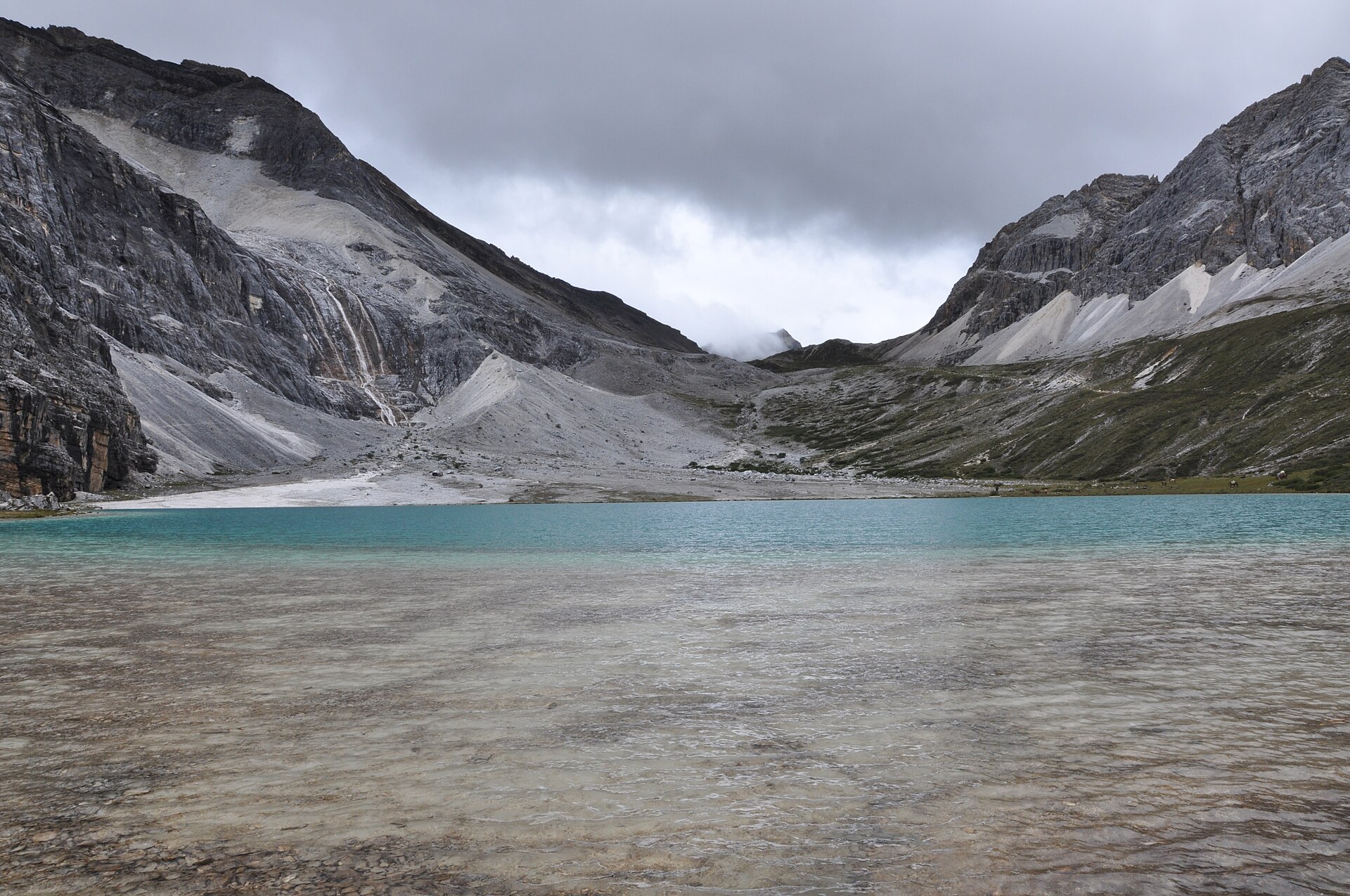 Turquoise Milk Lake lies below grey mountain slopes in Yading in August 2015.